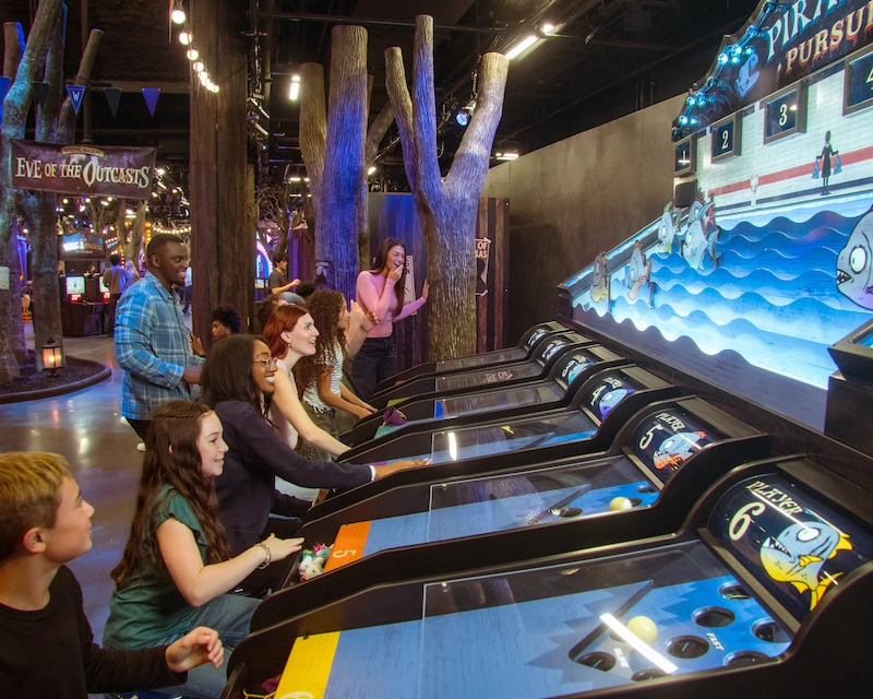 Friends play a carnival game in a Wednesday themed space.