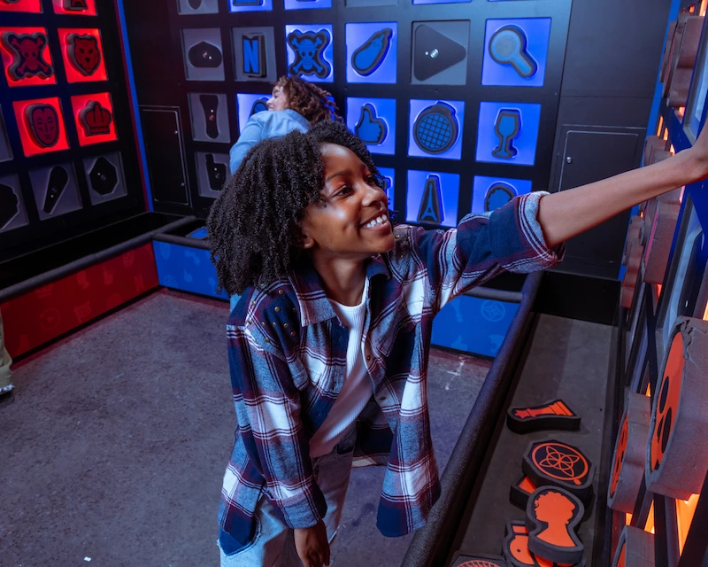 Child plays puzzle game in the RePLAY arcade room at Netflix House Dallas.