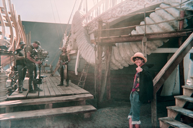 Jacob Romero as Usopp and Iñaki Godoy as Monkey D. Luffy stand in front of a pirate ship set in Season 1 of 'One Piece.'