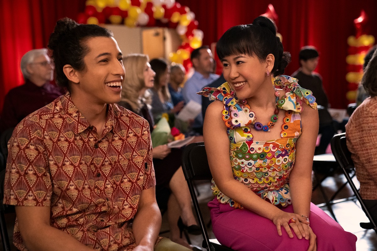 Benjamin Norris as Trent and Ramona Young as Eleanor Wong sit together smiling in ‘Never Have I Ever’ Season 3. 