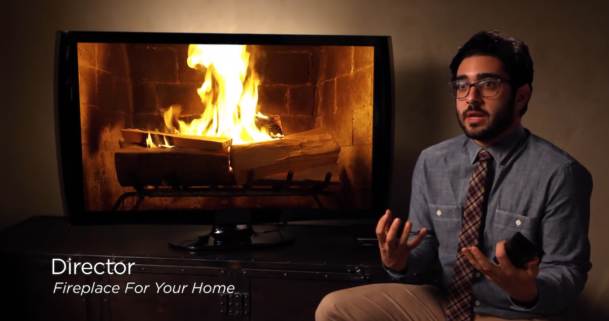 The director of Fireplace For Your Home sitting in front of a TV.