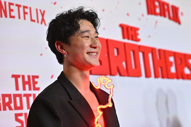 Sam Song Li attends Netflix's 'The Brothers Sun' Los Angeles Premiere and smiles against the step and repeat