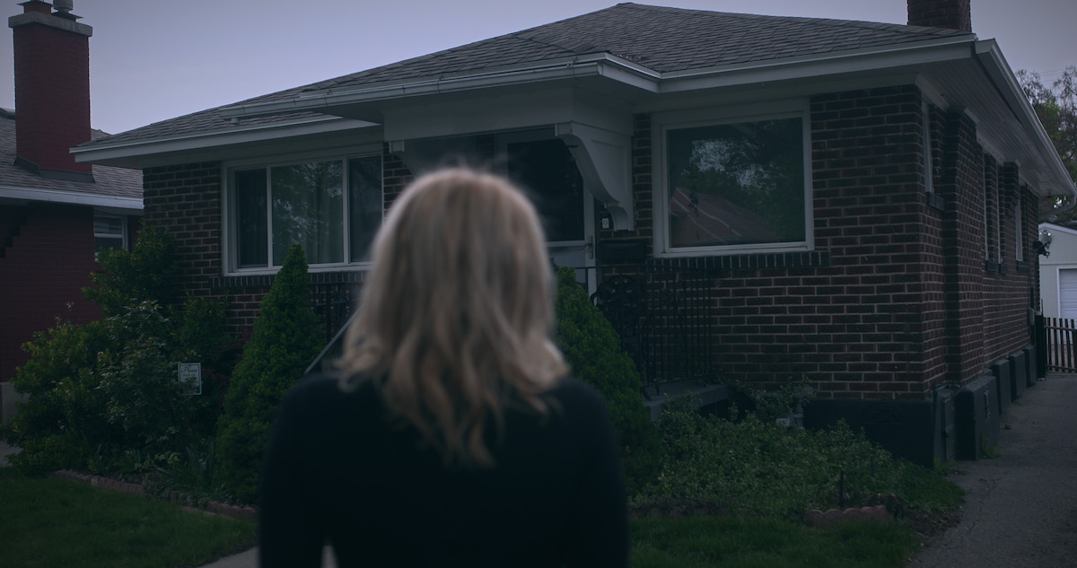 Rachel in the foreground looks at a house.