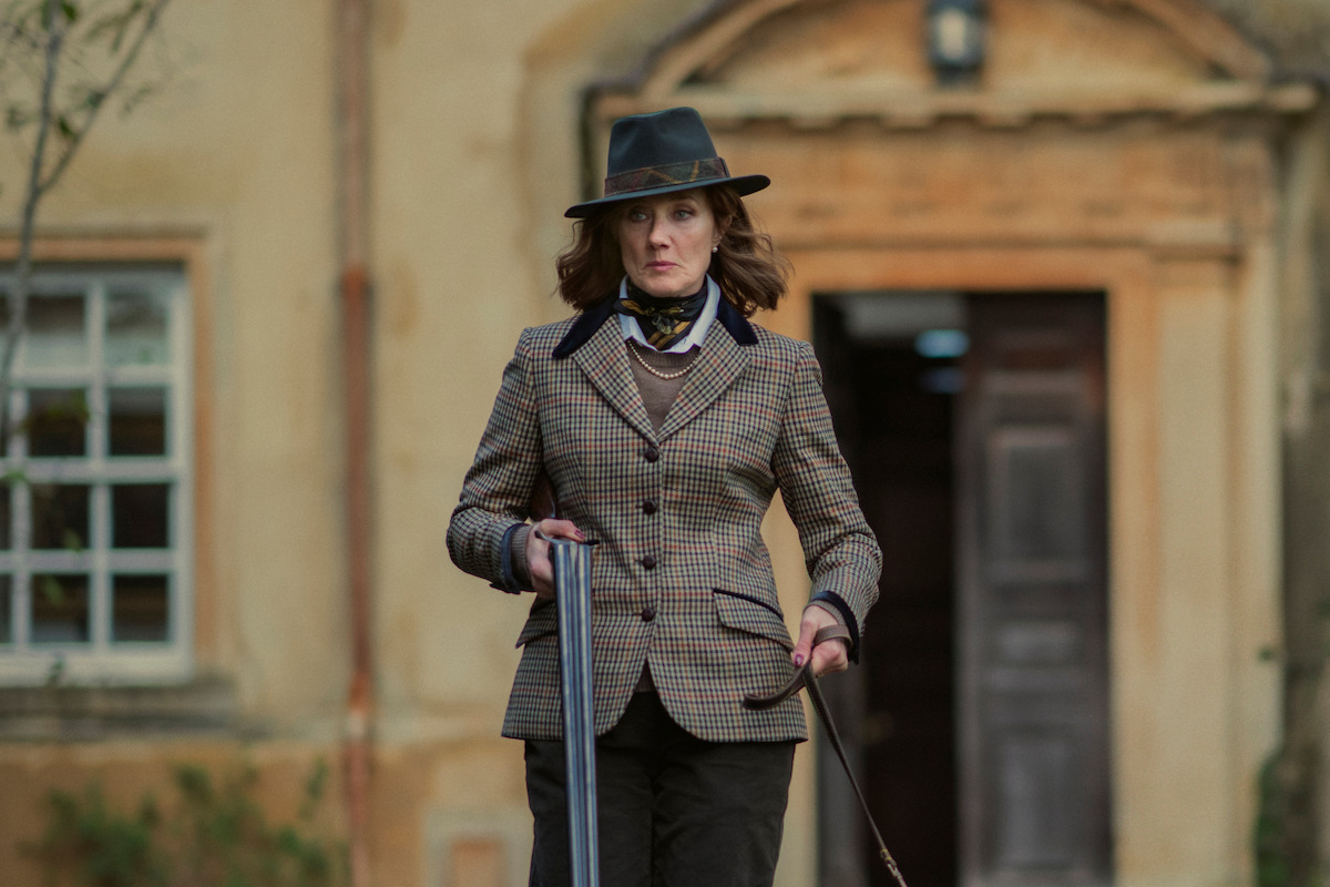 Joely Richardson as Lady Sabrina walking, wearing a tweed jacket and holding a shotgun in Season 1 of ‘The Gentlemen’