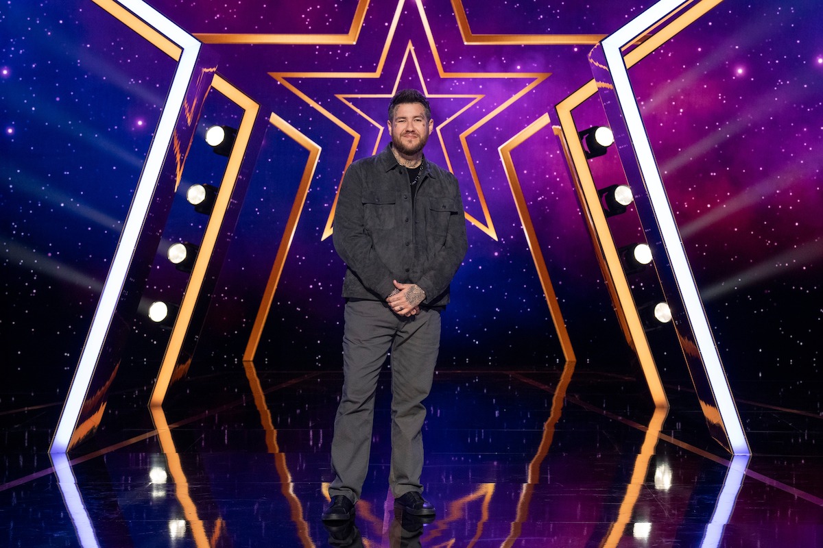 Bear Bailey on a shiny stage with a large illuminated star backdrop and colorful purple and blue lights, creating a vibrant, show-like atmosphere.