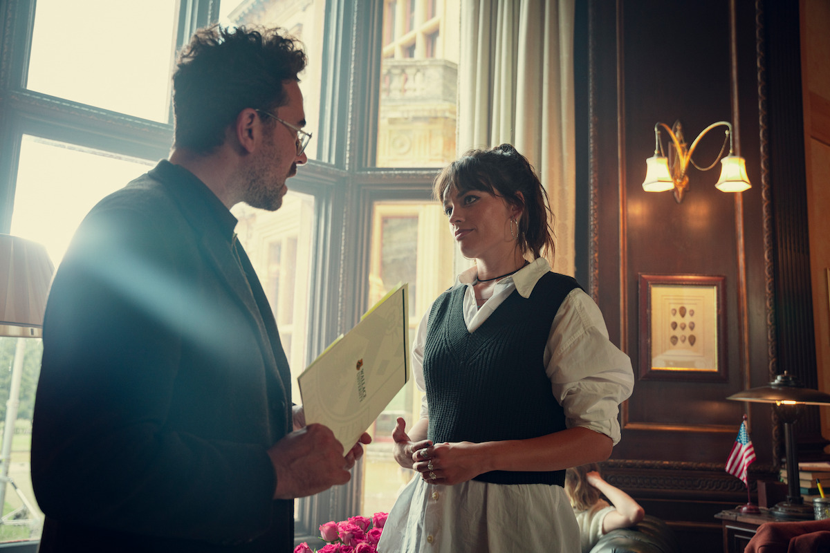  Dan Levy as Thomas and Emma Mackey as Maeve speak together in an office in Season 4 of ‘Sex Education.’ 