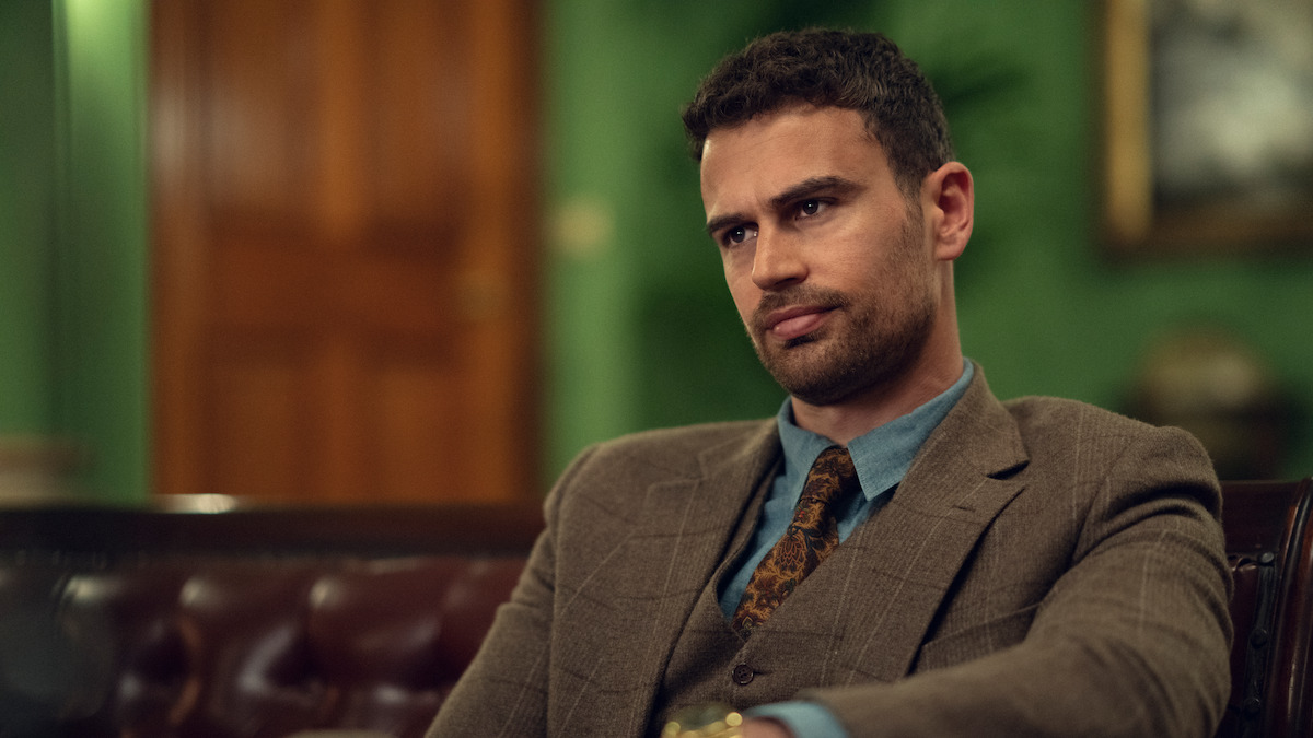 Theo James as Eddie Horniman sits on a tufted leather sofa in season 1 of ‘The Gentlemen’