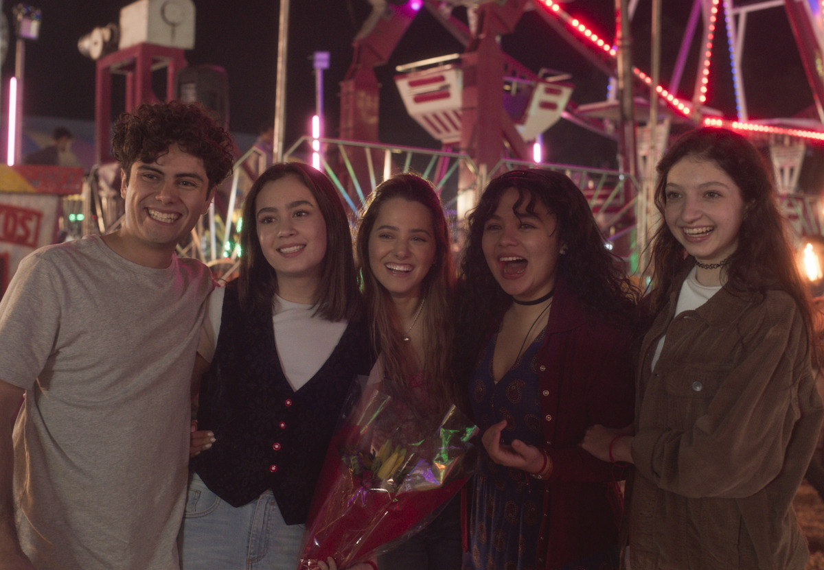 Five teens with their arms around each other pose for a photo in a still image from ‘Pact of Silence’