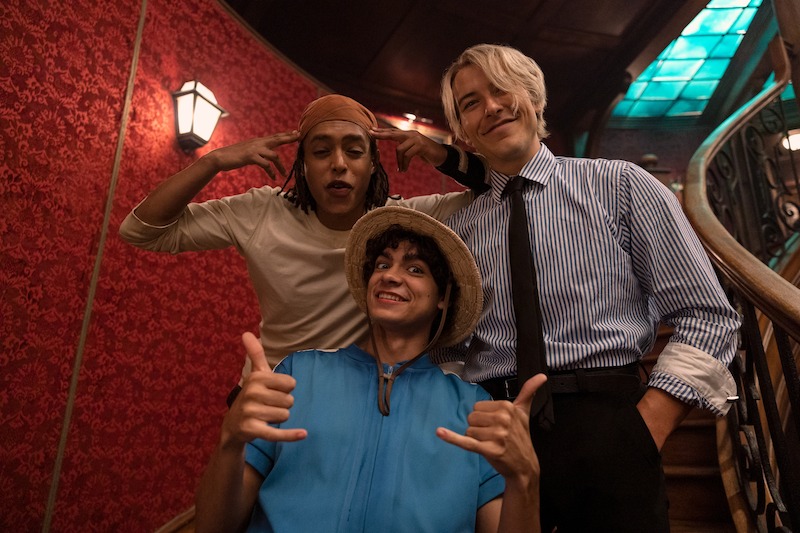 Jacob Romero as Usopp, Iñaki Godoy as Monkey D. Luffy, and Taz Skylar as Sanji pose on a staircase together in Season 1 of 'One Piece.'