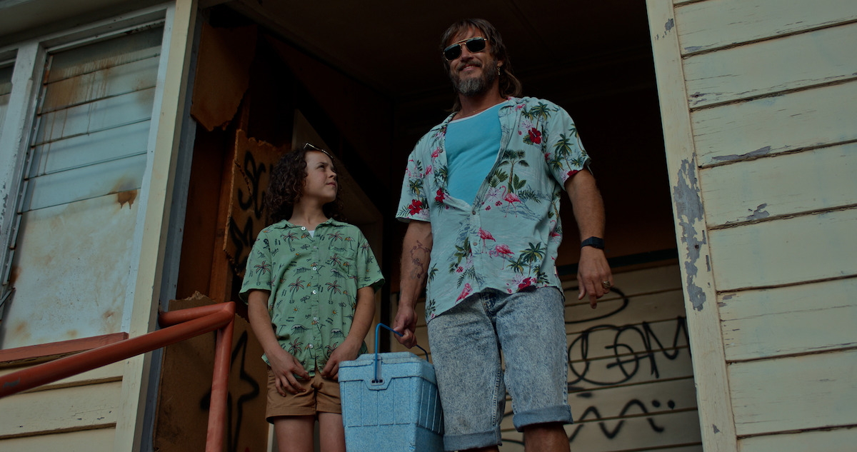 two people standing on the porch of a dilapidated house. 