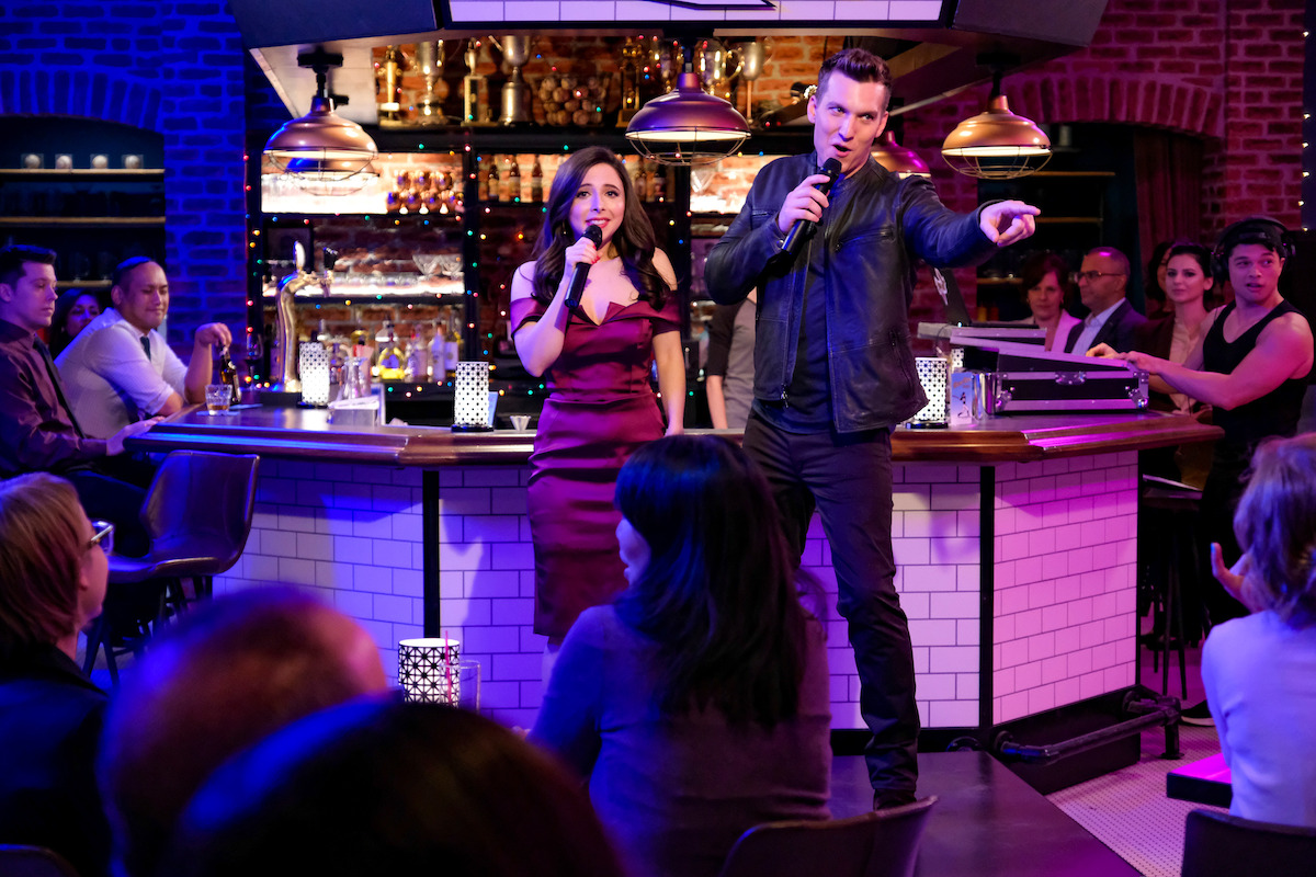 a man and a woman sing together at a bar. 