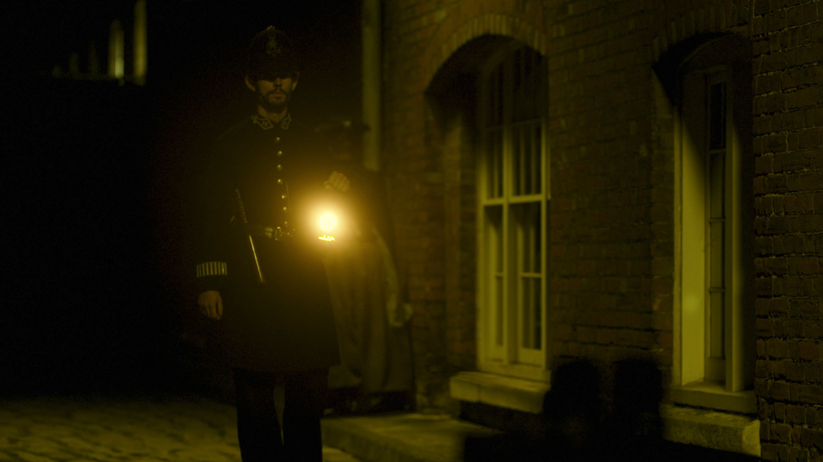 A police officer holds up a lantern.
