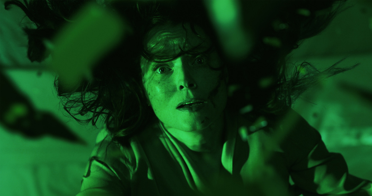 A woman looking up as glass falls on her. 