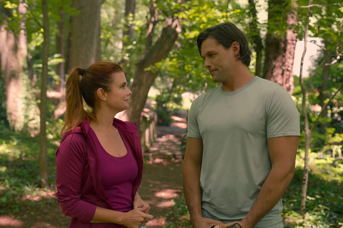 JoAnna Garcia Swisher as Maddie and Justin Bruening as Cal, wearing athletic clothes and looking into each other’s eyes in Season 3 of ‘Sweet Magnolias.’