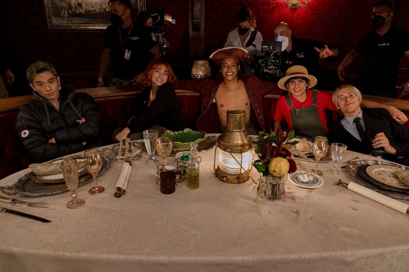 Mackenyu as Roronoa Zoro, Emily Rudd as Nami, Jacob Romero as Usopp, Iñaki Godoy as Monkey D. Luffy, and Taz Skylar as Sanji sit together in a booth in a restaurant in season 1 of 'One Piece.'