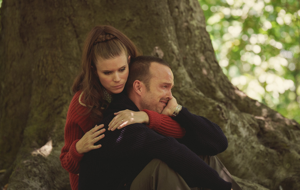 Kate Mara as XX hugging Aaron Paul as XX while seated in front of a tree in Season 6 of Black Mirror.