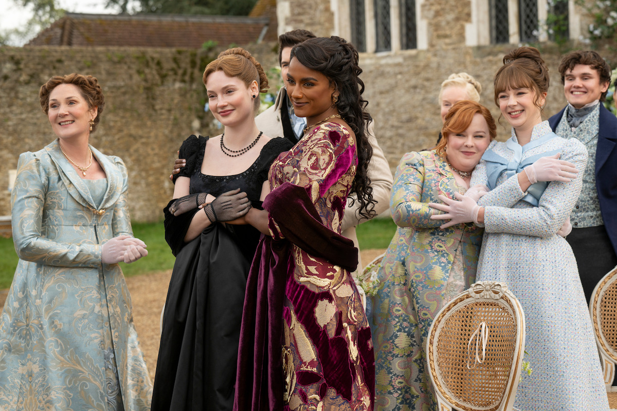 Five women smile in regency attire at a wedding