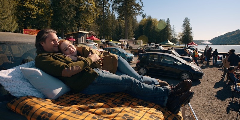 Alexandra Breckenridge as Mel Monroe and Martin Henderson as Jack Sheridan lounge at a drive-in theater together in Season 6 of 'Virgin River'