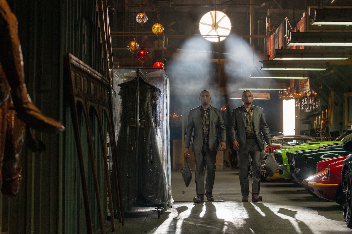 The Twins entering a warehouse with exotic cars