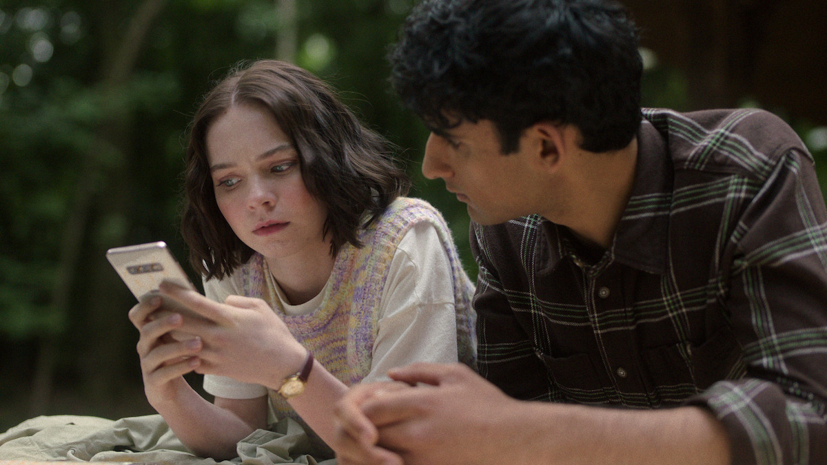 Emma Myers as Pip looks at a phone with Zain Iqbal as Ravi in ‘A Good Girl’s Guide to Murder’