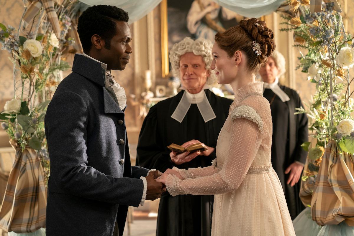 Victor Alli as John Stirling and Hannah Dodd as Francesca Bridgerton hold hands at their wedding ceremony in Season 3 of ‘Bridgerton.’