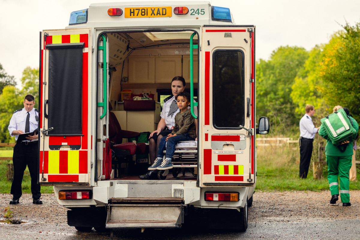 An EMT sits in the back of an ambulance with a small boy at the scene of a crime. Unable to generate alt text. Please manually enter a description for this asset.