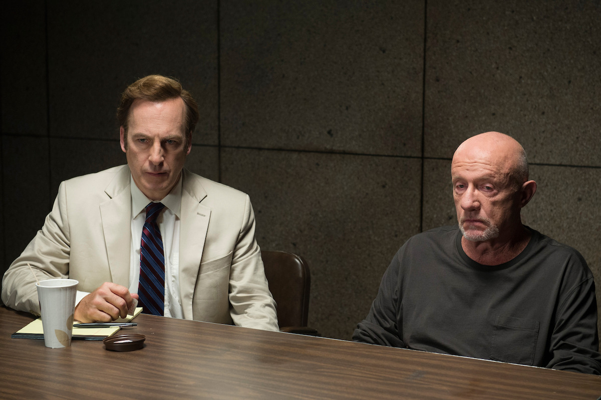 Saul Goodman and Mike Ermentraut sitting behind a desk in a police interrogation room