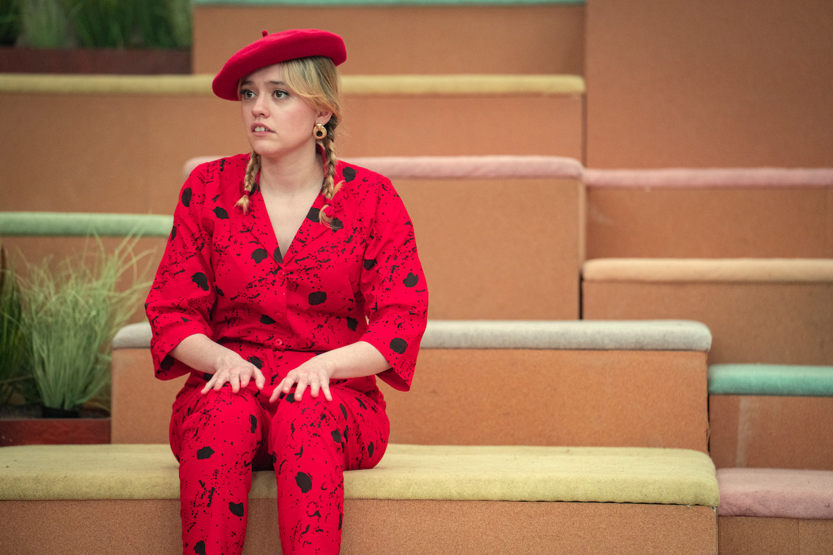 Aimee Lou Wood as Aimee wears a red blouse and matching pants paired with a red beret in Season 4 of ‘Sex Education.’