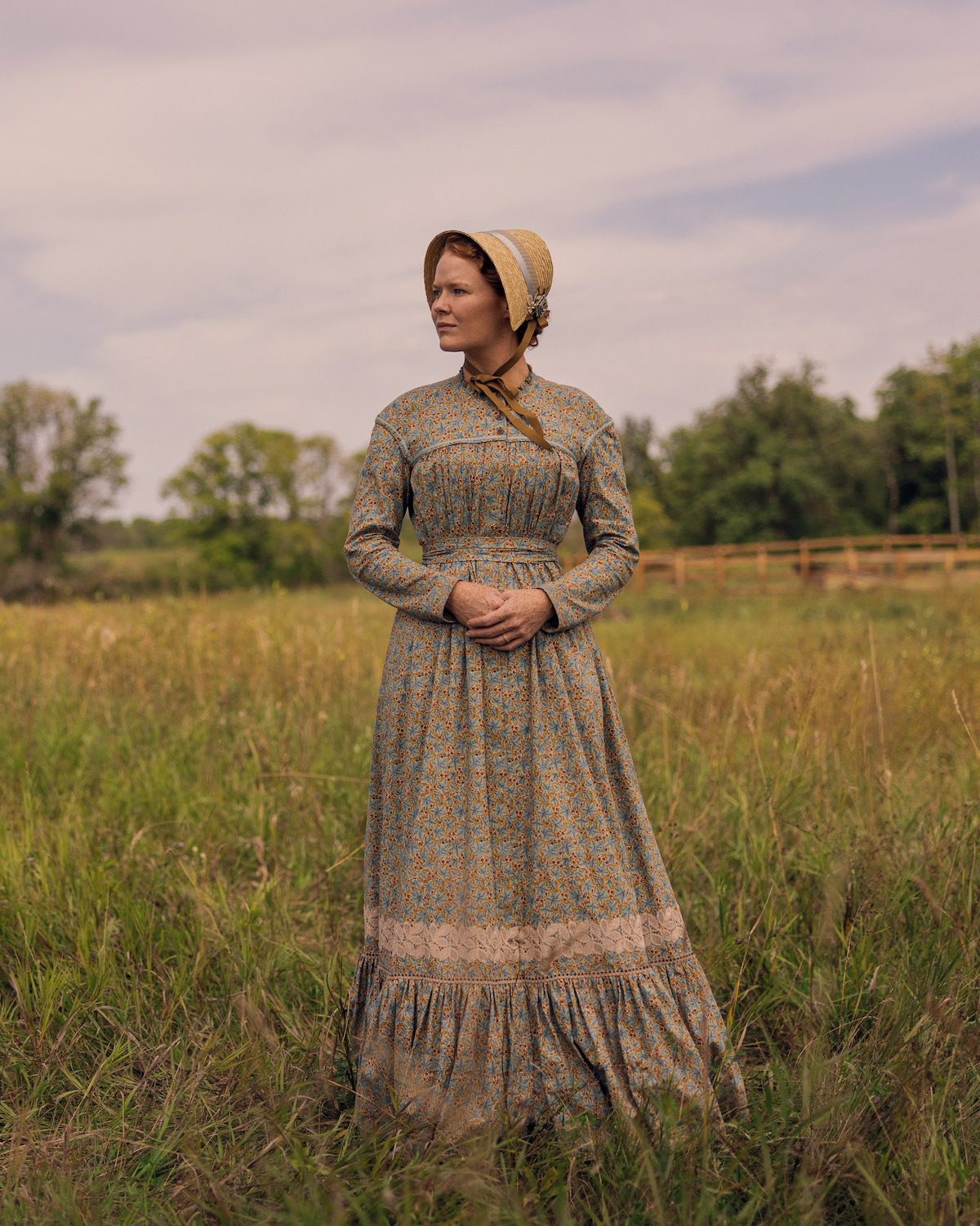 A woman in a field looks off into the distance.