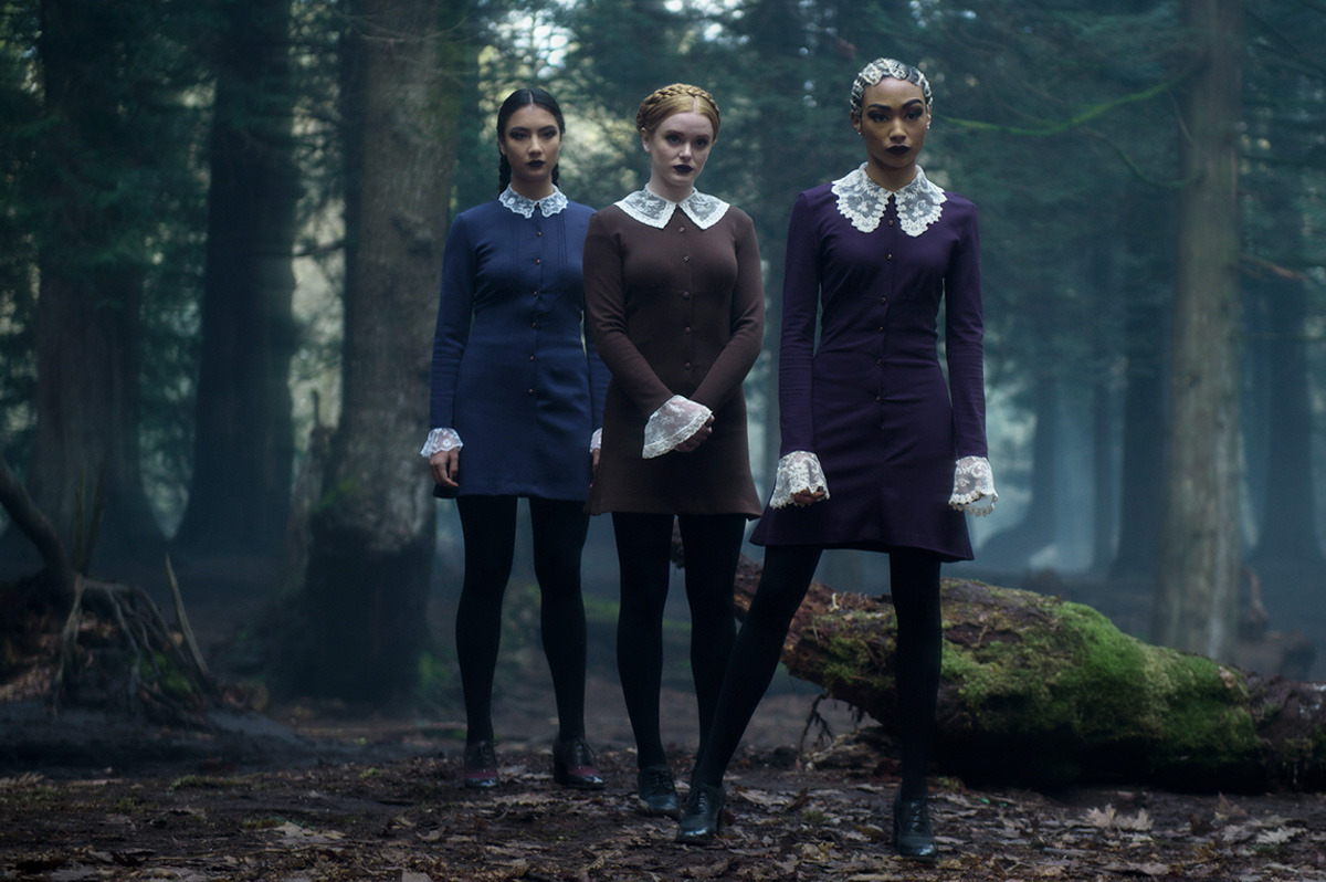  Three women in matching dresses standing in the woods.