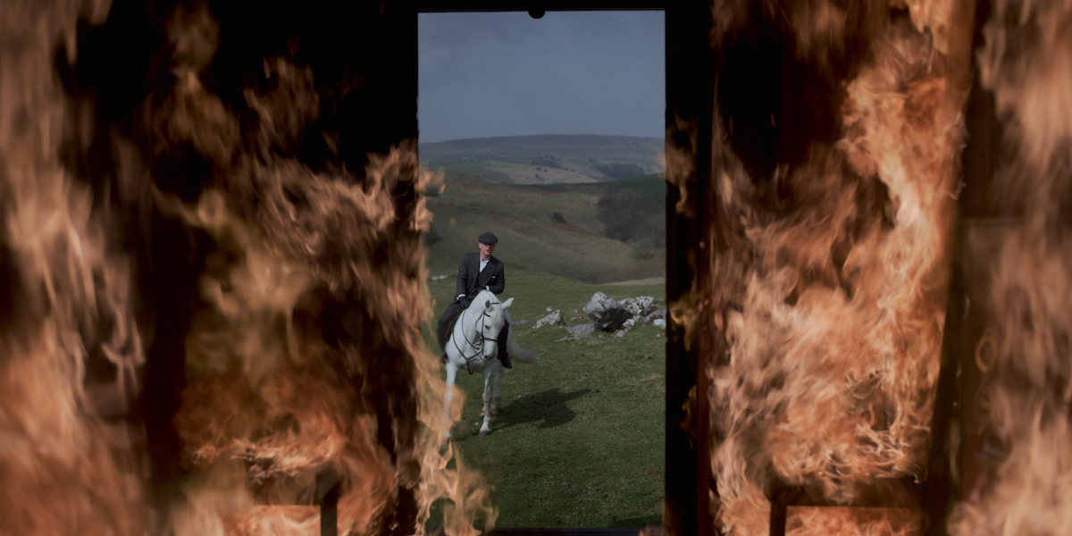 Tommy rides away from his camp, which is now on fire