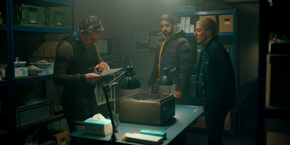 Carla Sehn and Kardo Razzazi look on as a man surveys a document in an image from ‘The Åre Murders.’