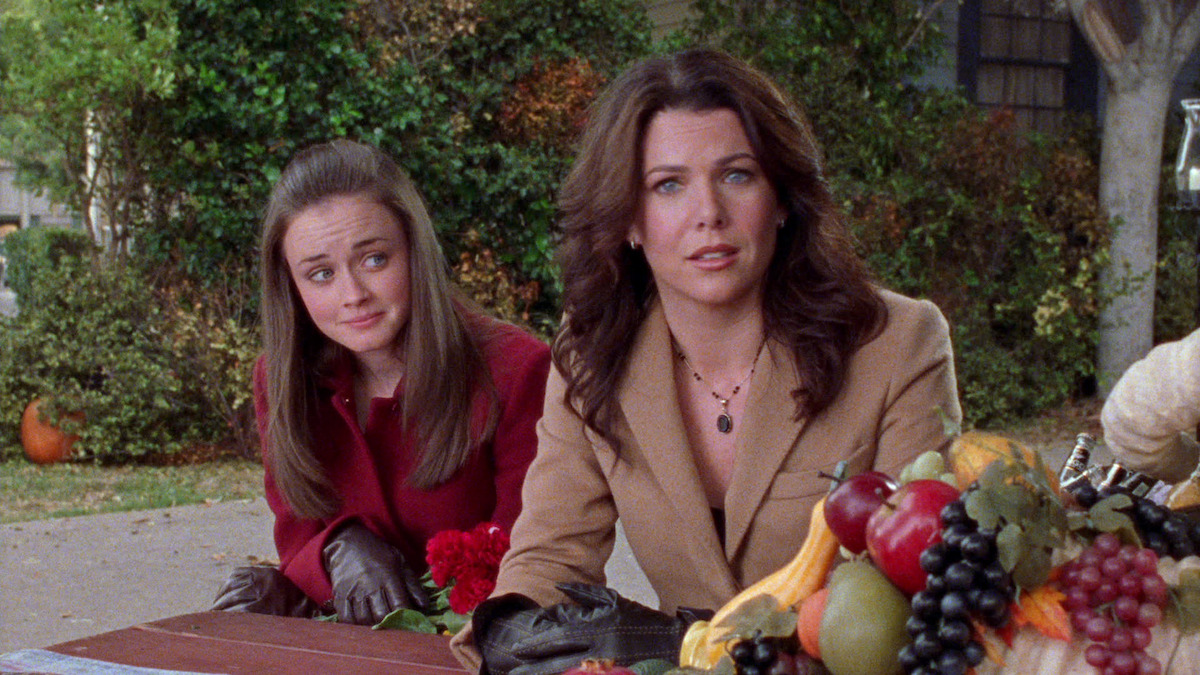 Rory and Lorelai look concerned and amused at the thanksgiving cornocopia on the table. 