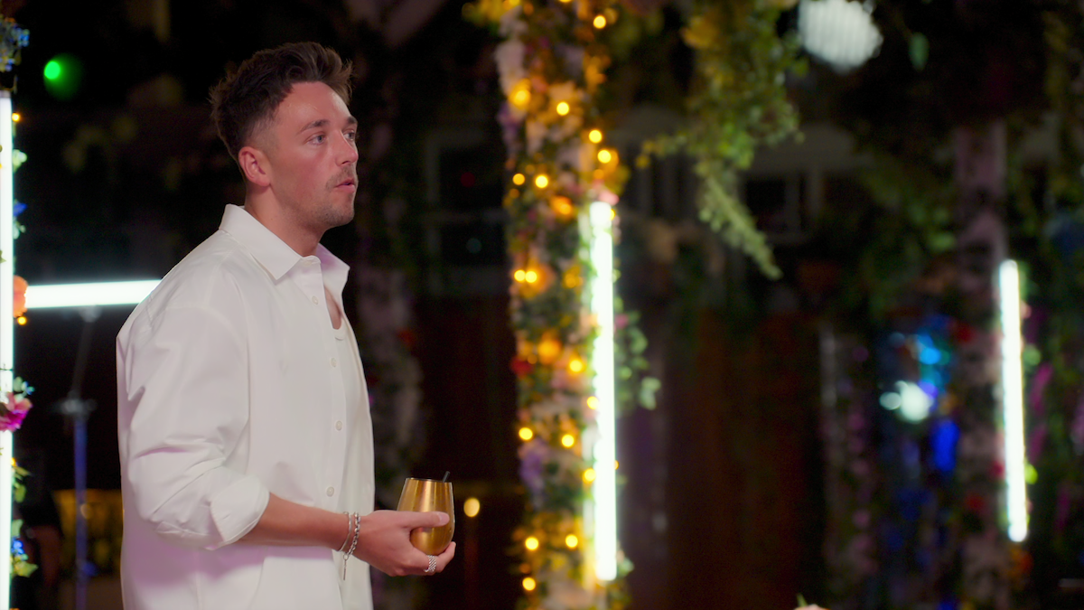 Sam holds a drink in his hand.