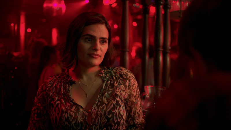 Nava Mau as Teri stands in a club shrouded in red light in 'Baby Reindeer'