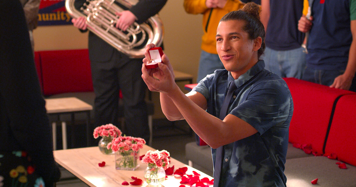Benjamin Norris as Trent in Season 4 of Never Have I Ever, kneeling and holding an open ring box.