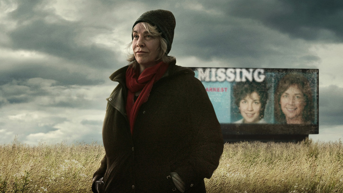  Cathy Terkanian standing in a field with a missing persons billboard in the background.