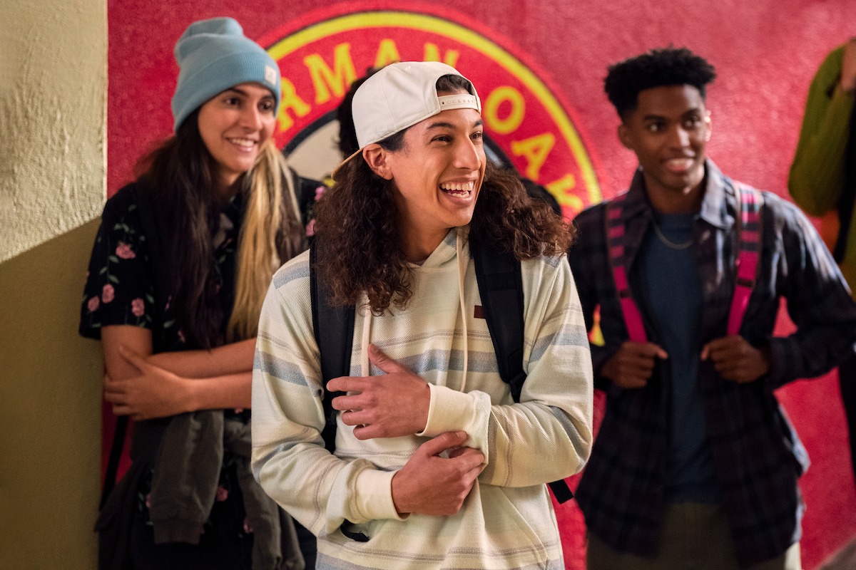 Benjamin Norris as Trent in Never Have I Ever Season 4 smiles in a high school hallway. 