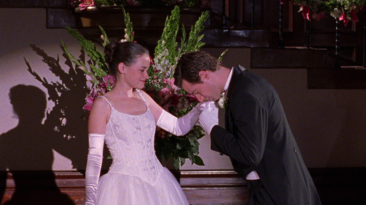 A young woman in a white dress is presented at a debutante ball