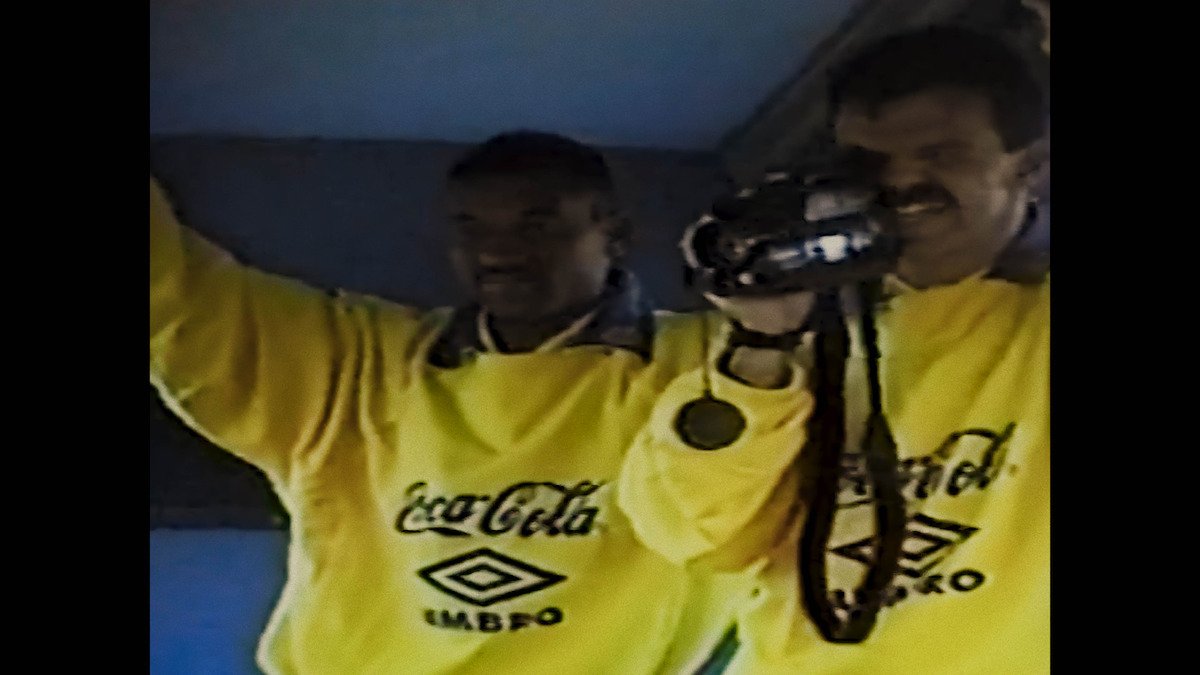 Two teammates on Brazil's 1994 World Cup team capturing footage on a camcorder.