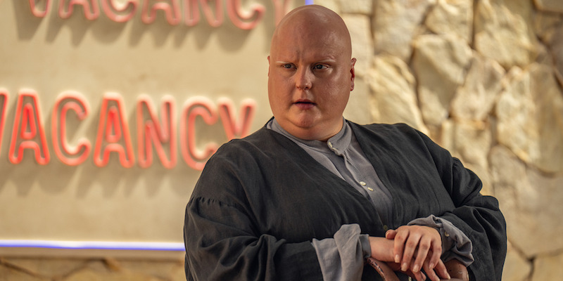 A bald man sits leaning on his arm in Seaosn 1 of 'Kaos'