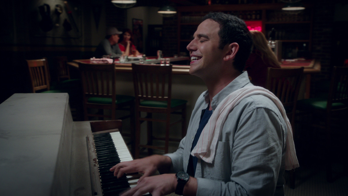 a man playing piano with a bar towel over his shoulder. 