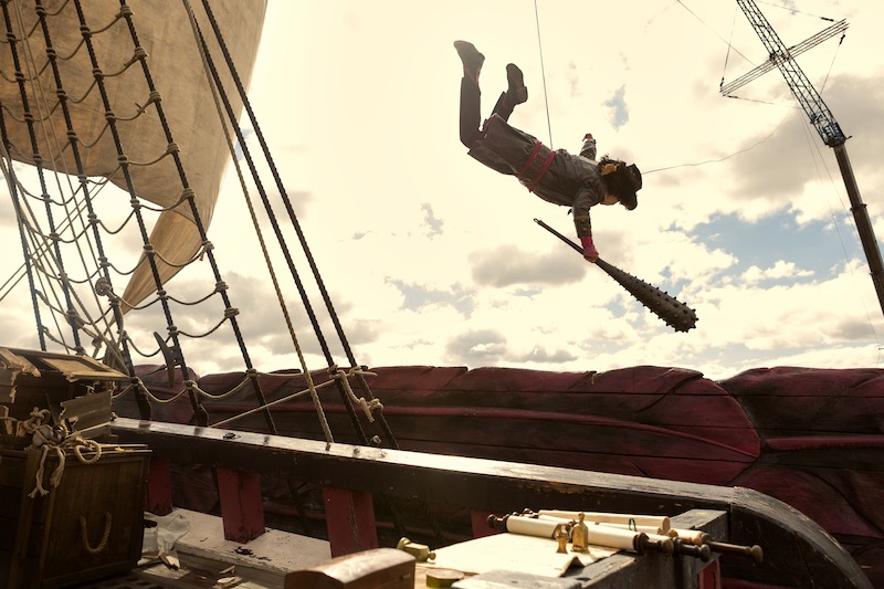 A stunt performer flies through the air holding a club on the set of Season 1 of 'One Piece.'