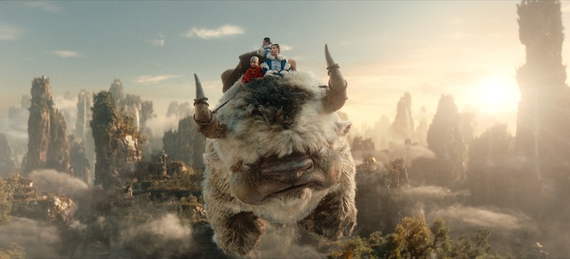 Gordon Cormier as Aang, Ian Ousley as Sokka, and Kiawentiio as Katara ride Appa, the flying water buffalo, in Season 1 of Avatar: The Last Airbender'