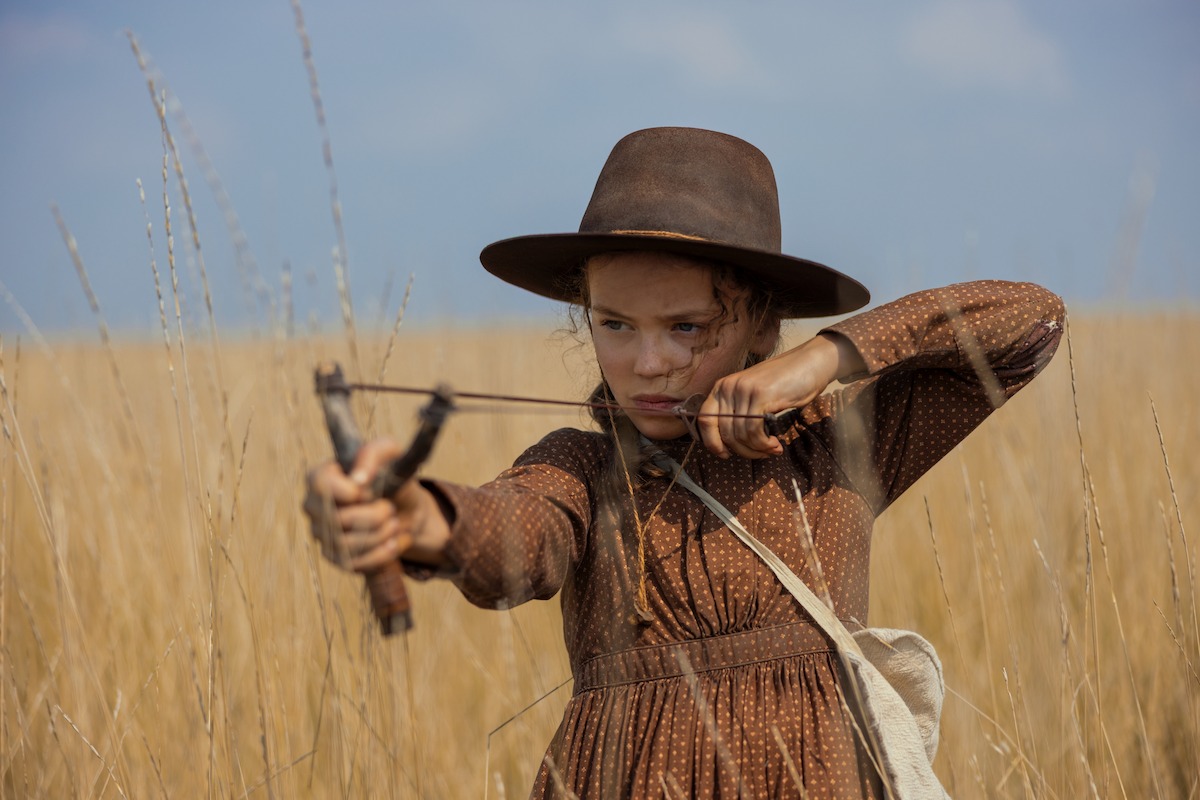 A young girl draws back on a slingshot and takes aim.