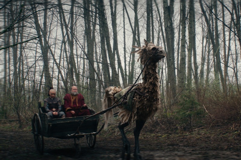 Dallas Liu as Prince Zuko and Paul Sun-Hyung Lee as Iroh ride in a chariot pulled by a large creature in season 1 of 'Avatar: The Last Airbender'