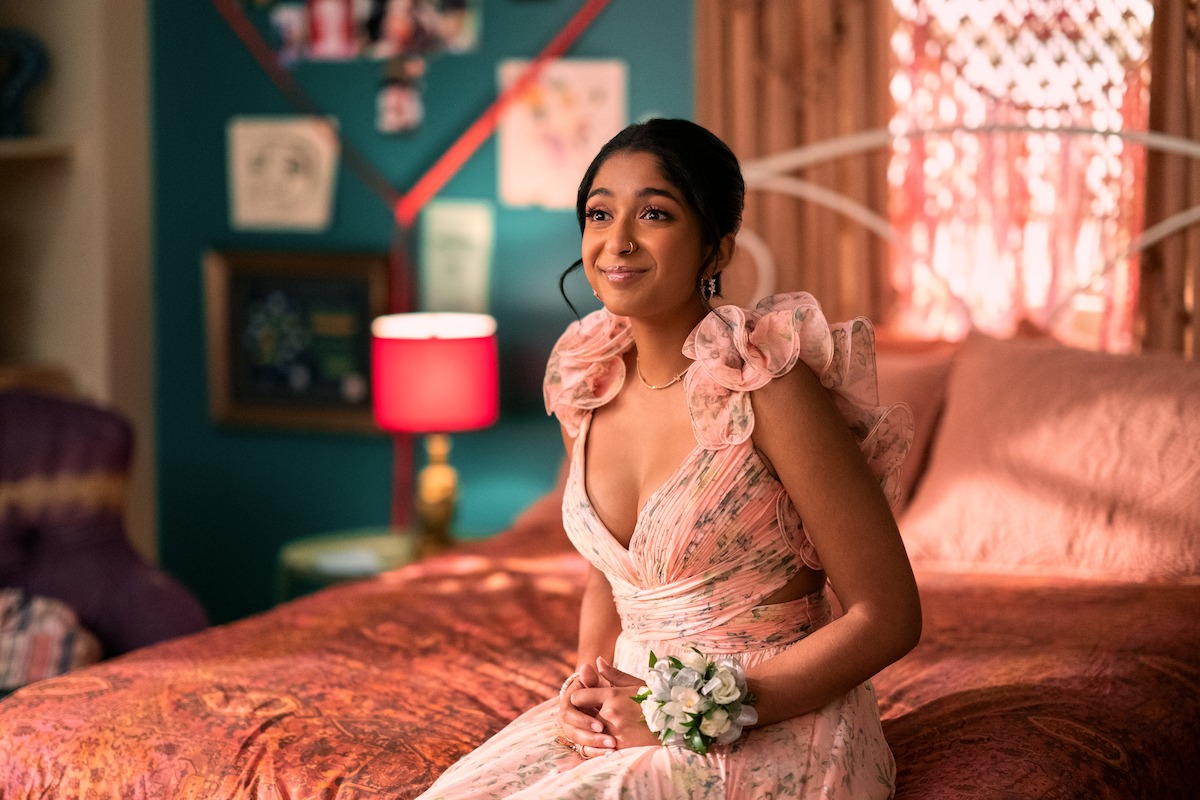 Maitreyi Ramakrishnan as Devi sits on a bed wearing a formal dress in Season 4 of ‘Never Have I Ever.’ 