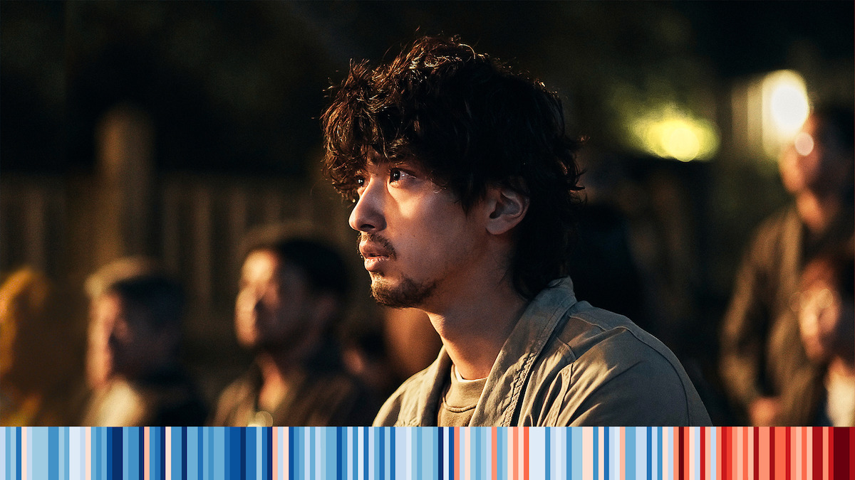 a bearded man looks off-screen with concern. 