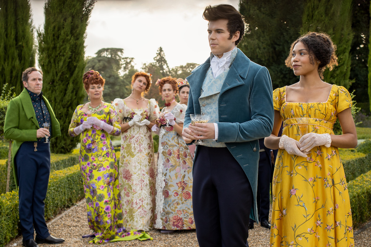 Ben Miller as Lord Featherington, Polly Walker as Portia Featherington, Bessie Carter as Prudence Featherington, Harriet Cains as Philippa Featherington, Luke Newton as Colin Bridgerton, and Ruby Barker as Marina Thompson in Episode 106 of ‘Bridgerton.’