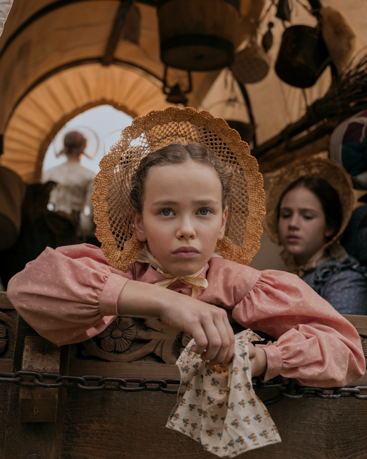 A girl looks out from a covered wagon.